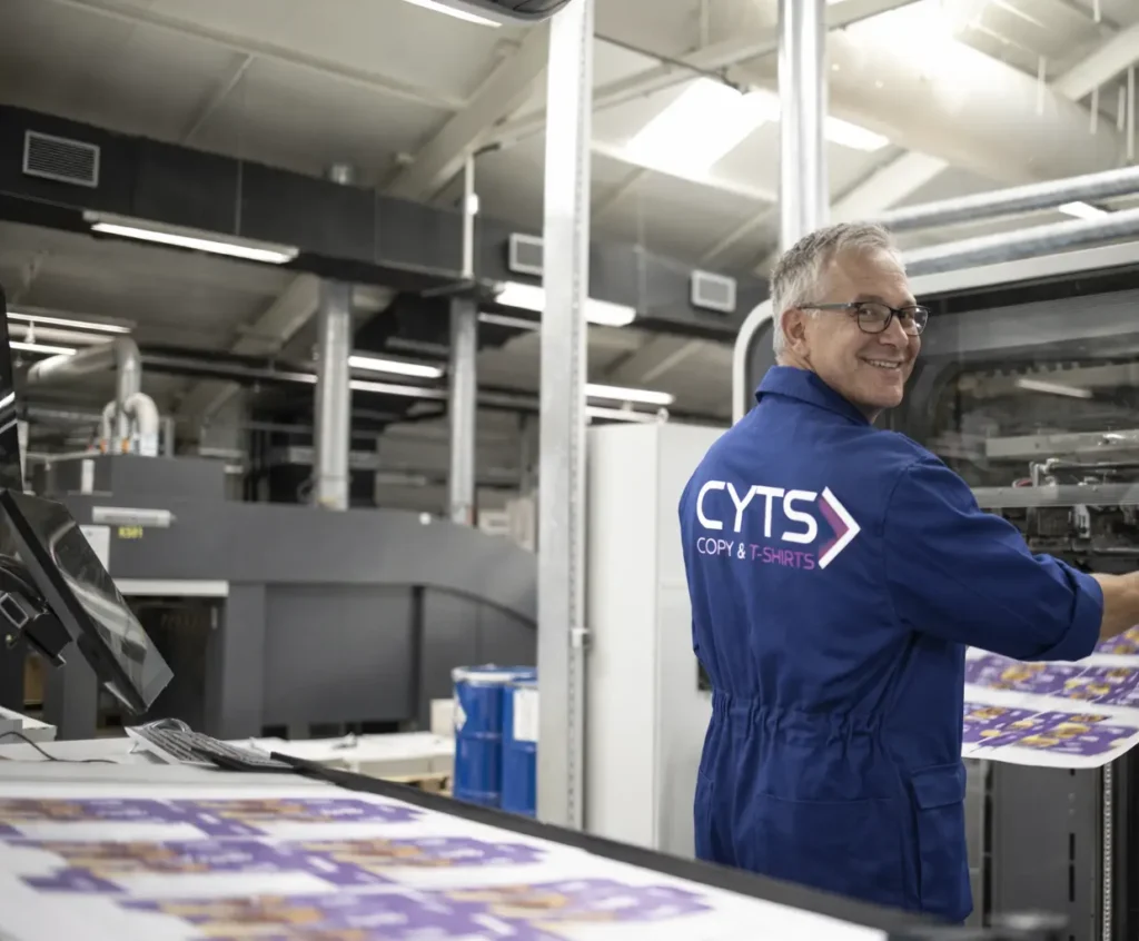 Operario de imprenta realizando control de calidad de impresión en máquina industrial